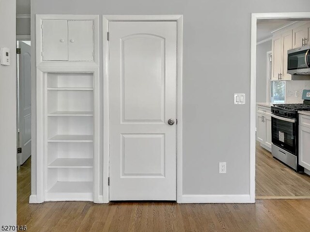 interior space featuring built in features, light hardwood / wood-style flooring, stainless steel appliances, and white cabinets