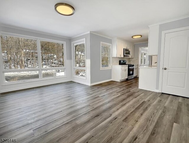 unfurnished living room with ornamental molding and dark hardwood / wood-style floors