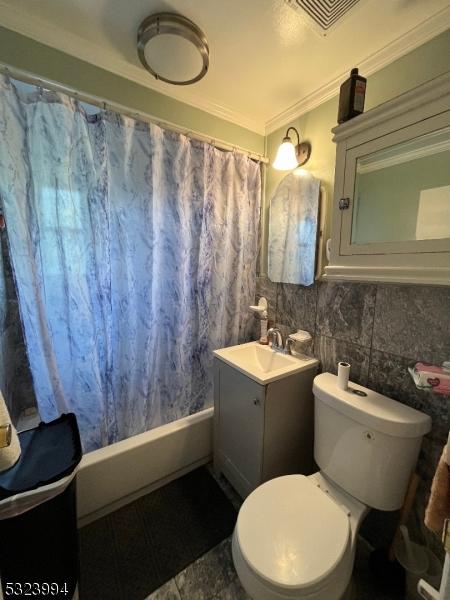 full bathroom with shower / tub combo with curtain, toilet, crown molding, tile walls, and vanity