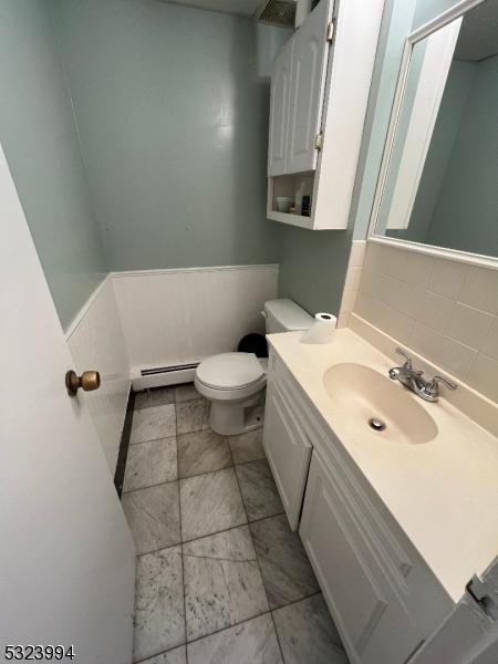 bathroom with a baseboard radiator, vanity, and toilet