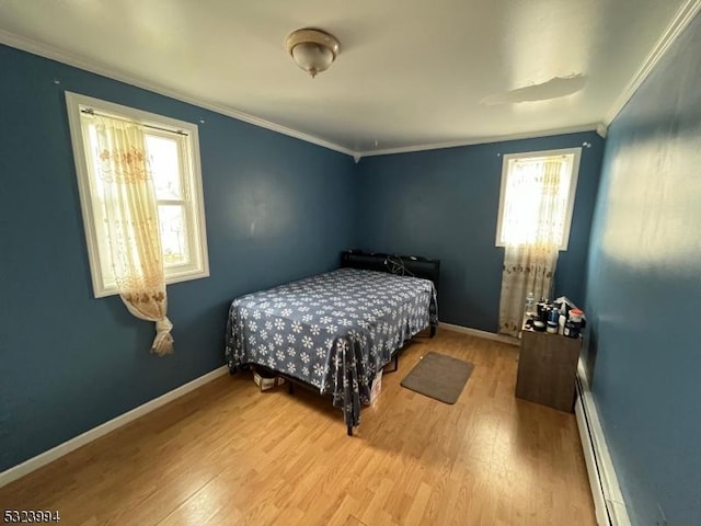 bedroom with multiple windows, a baseboard heating unit, wood-type flooring, and ornamental molding