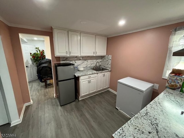 kitchen with sink, stainless steel refrigerator, refrigerator, backsplash, and white cabinets