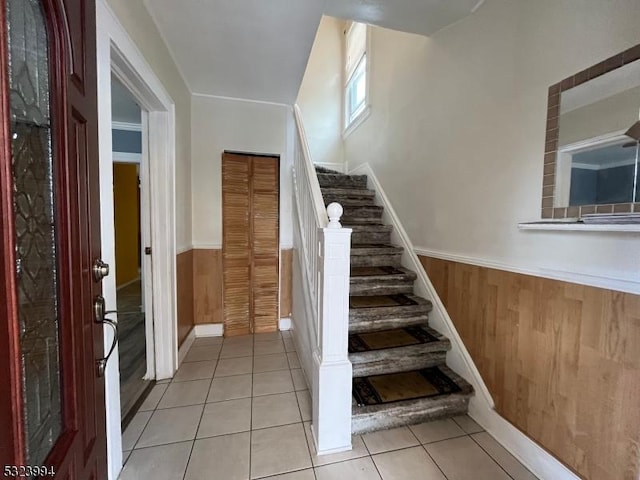 stairway with tile patterned flooring and wood walls