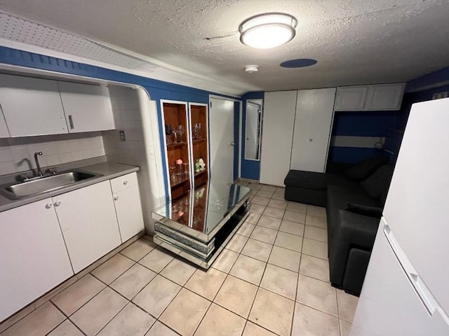 kitchen with white cabinetry, sink, a textured ceiling, and light tile patterned floors