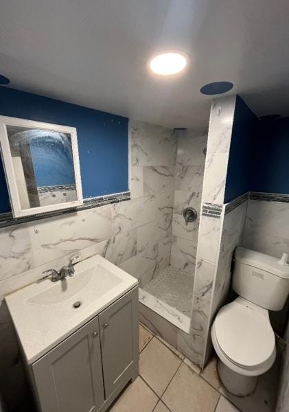 bathroom featuring tiled shower, vanity, toilet, and tile walls