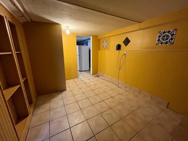 interior space featuring white refrigerator, light tile patterned floors, and a textured ceiling