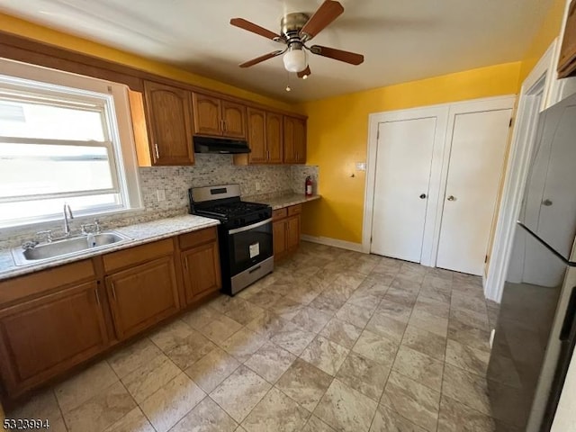 kitchen featuring tasteful backsplash, ceiling fan, sink, and stainless steel gas range oven