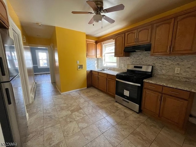 kitchen featuring tasteful backsplash, sink, fridge, gas range, and light stone countertops