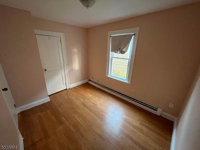 empty room featuring a baseboard radiator and wood-type flooring