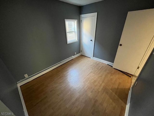 unfurnished bedroom featuring a baseboard radiator and light wood-type flooring