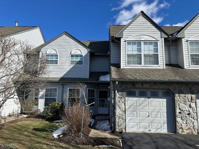 view of front of property with a garage, stone siding, a shingled roof, and aphalt driveway