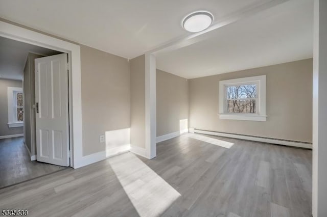 empty room featuring a baseboard heating unit and light hardwood / wood-style floors