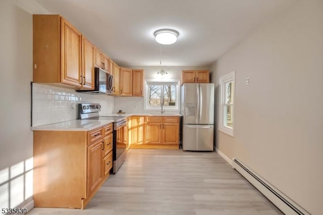 kitchen featuring a baseboard heating unit, stainless steel appliances, tasteful backsplash, light wood-type flooring, and light brown cabinets