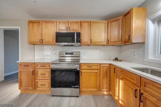 kitchen featuring tasteful backsplash, stainless steel appliances, and light hardwood / wood-style floors