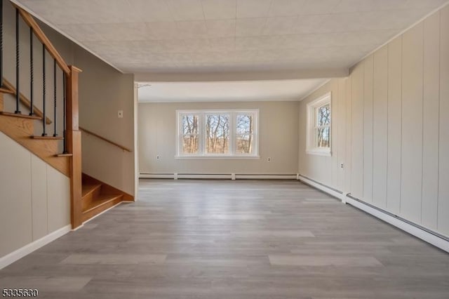 empty room with baseboard heating and light hardwood / wood-style flooring