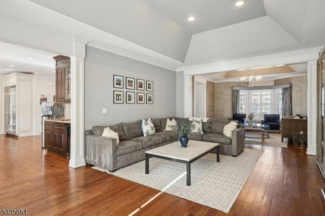 living room with decorative columns, a raised ceiling, hardwood / wood-style floors, and an inviting chandelier