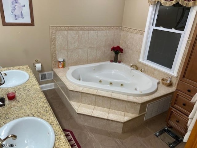 bathroom featuring vanity, a relaxing tiled tub, and tile patterned floors