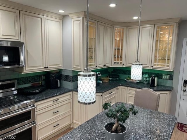 kitchen with dark stone countertops, cream cabinets, and stainless steel appliances