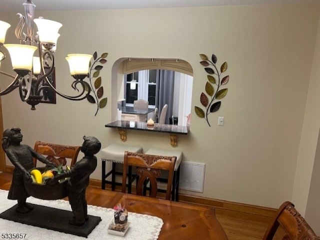 dining area featuring wood-type flooring and a notable chandelier