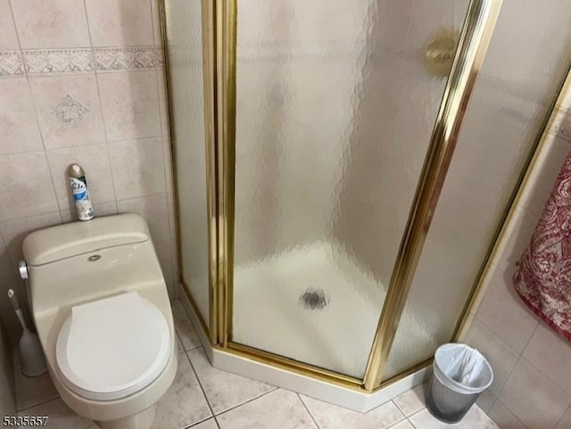 bathroom featuring tile walls, tile patterned flooring, a shower with door, and toilet