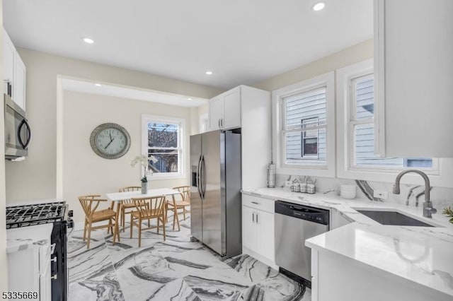 kitchen featuring stainless steel appliances, light stone countertops, sink, and white cabinets