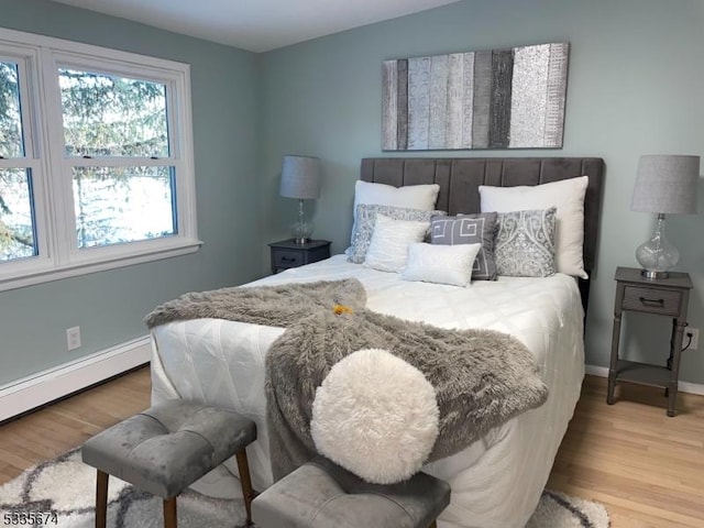 bedroom with baseboards, baseboard heating, and wood finished floors