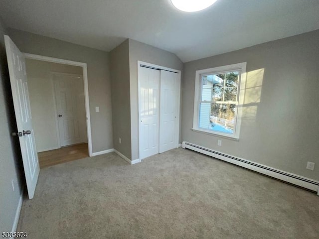 unfurnished bedroom with a baseboard radiator, baseboards, vaulted ceiling, a closet, and carpet