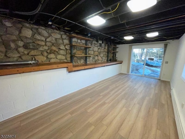 basement with a baseboard heating unit and wood finished floors