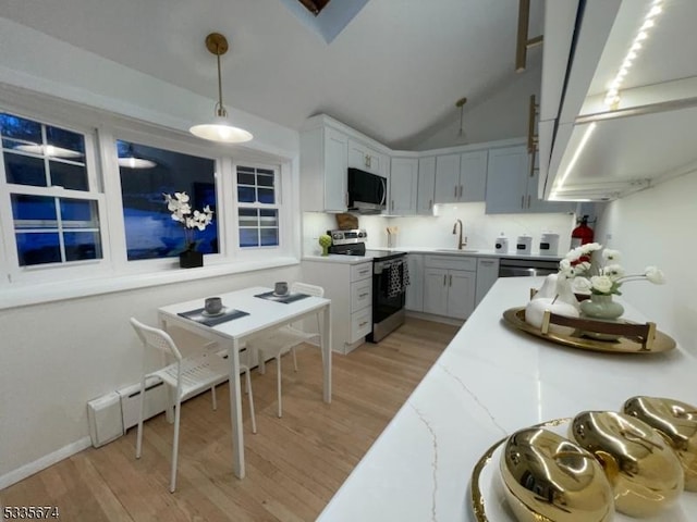 kitchen featuring light wood-style floors, vaulted ceiling, appliances with stainless steel finishes, and pendant lighting