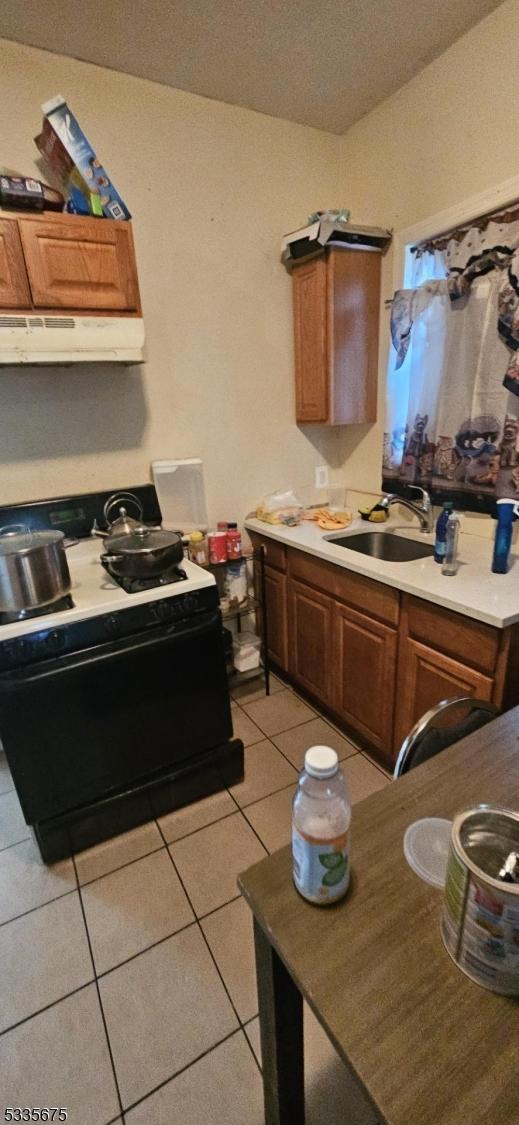 kitchen with light tile patterned floors, sink, and stove