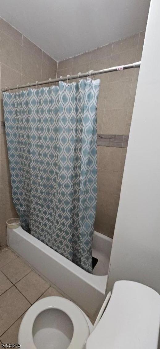 bathroom featuring tile patterned flooring, shower / bath combo with shower curtain, and toilet