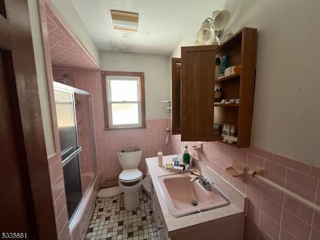 full bathroom with enclosed tub / shower combo, toilet, sink, and tile walls