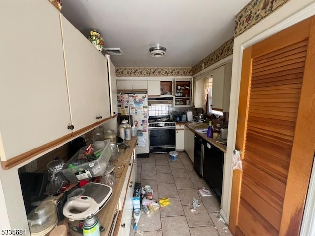 kitchen with white cabinetry, light tile patterned floors, tasteful backsplash, and stove