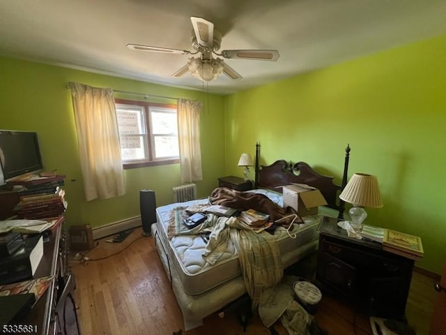 bedroom featuring hardwood / wood-style flooring, radiator heating unit, ceiling fan, and baseboard heating