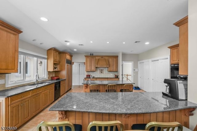 kitchen with a kitchen bar, sink, black dishwasher, kitchen peninsula, and decorative backsplash