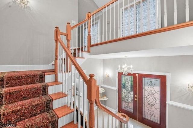 stairs with a towering ceiling and a notable chandelier