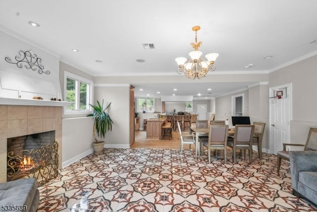 living room with a tile fireplace, an inviting chandelier, and crown molding