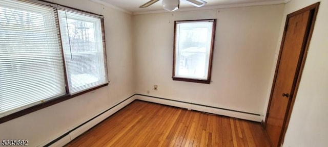 empty room with ceiling fan, crown molding, baseboard heating, and light hardwood / wood-style flooring