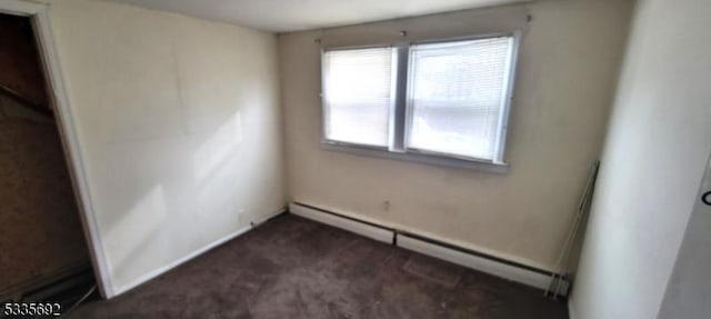 carpeted empty room with a baseboard heating unit