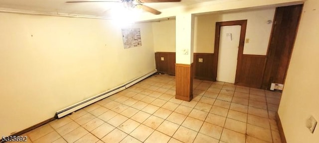 spare room featuring light tile patterned floors, wooden walls, ceiling fan, and baseboard heating