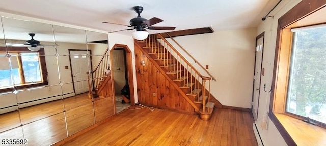 interior space featuring a baseboard heating unit, wood-type flooring, and ceiling fan