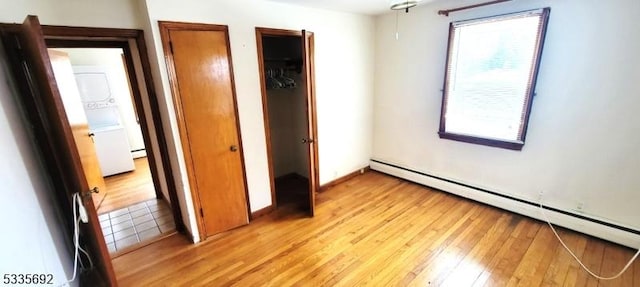 unfurnished bedroom with light wood-type flooring and baseboard heating