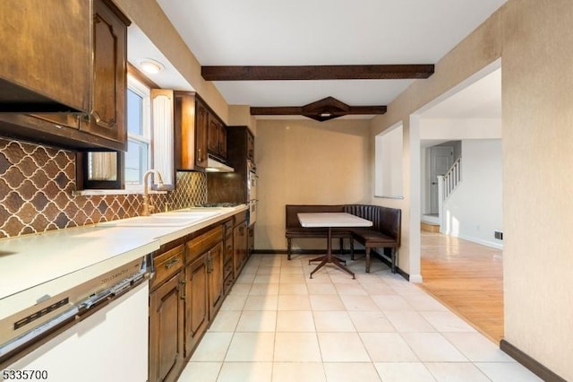 kitchen with beam ceiling, dishwasher, sink, and decorative backsplash