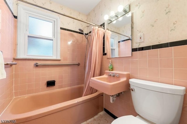 bathroom featuring tile walls, shower / bath combination with curtain, and toilet