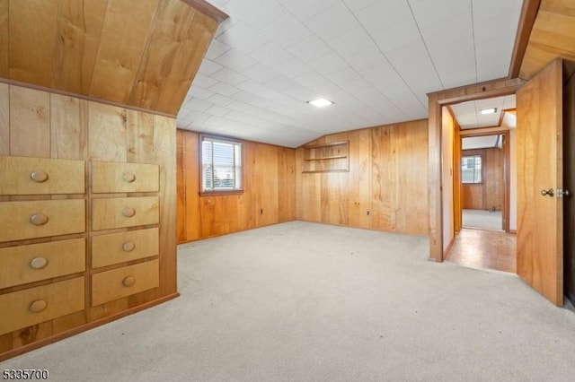 basement featuring wooden walls and light carpet