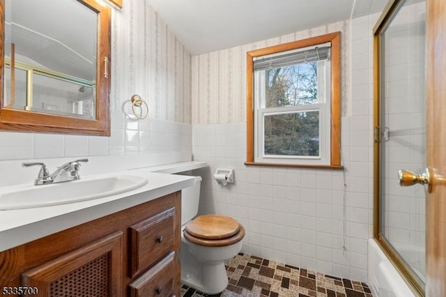 full bathroom with vanity, tile walls, bath / shower combo with glass door, and toilet