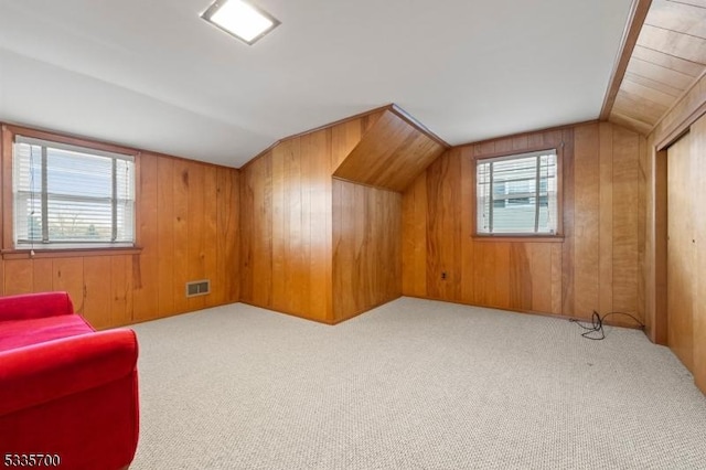 bonus room featuring lofted ceiling, wooden walls, and light colored carpet