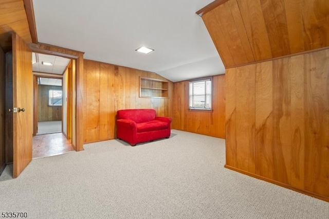 sitting room with light colored carpet, lofted ceiling, and wooden walls