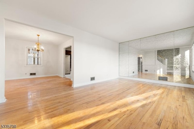 spare room featuring hardwood / wood-style flooring and a notable chandelier