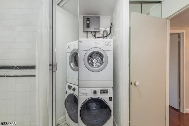 clothes washing area with stacked washer / dryer, dark hardwood / wood-style floors, and electric panel